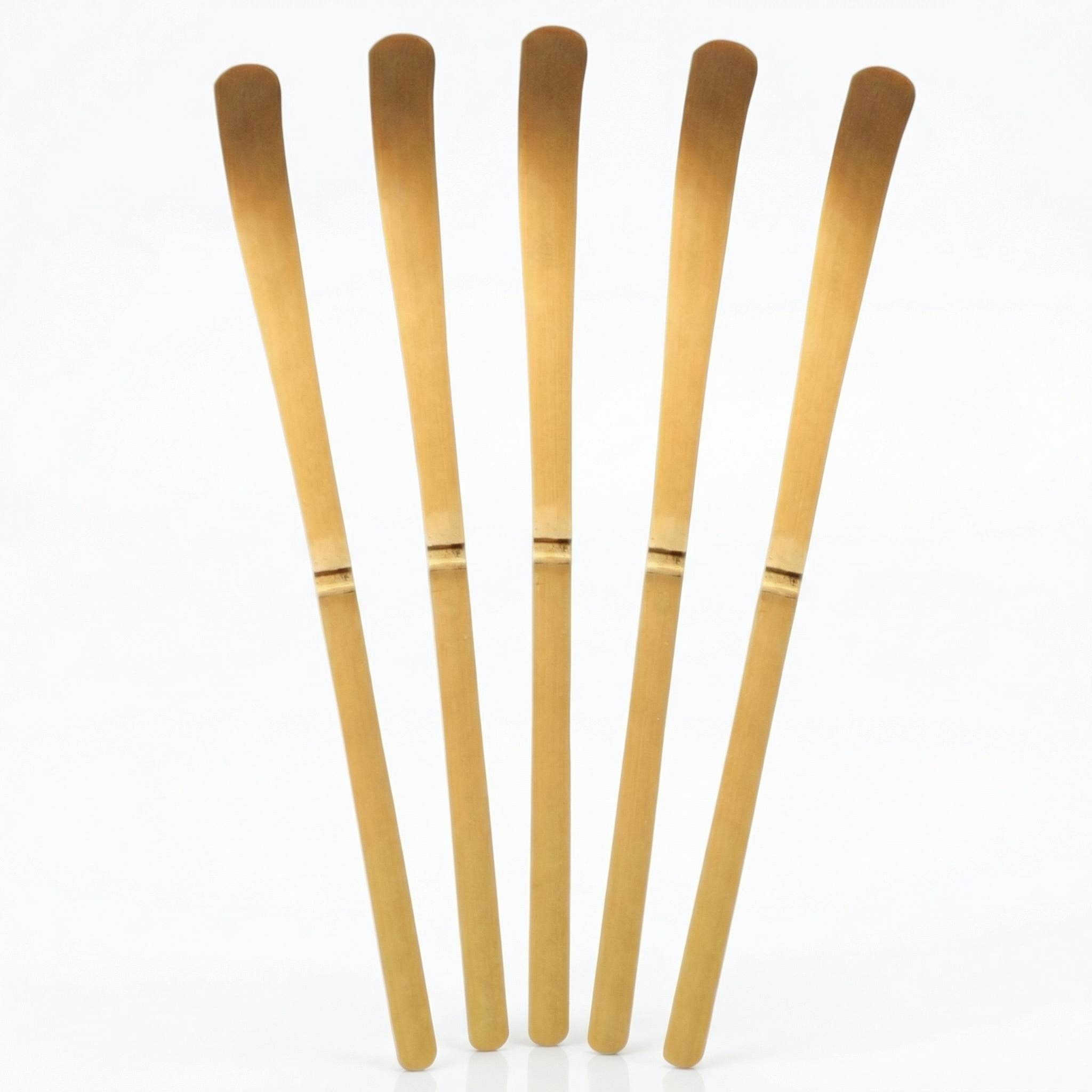 Cinq chashaku cuillères doseuses matcha en bambou naturel fond blanc avec reflet