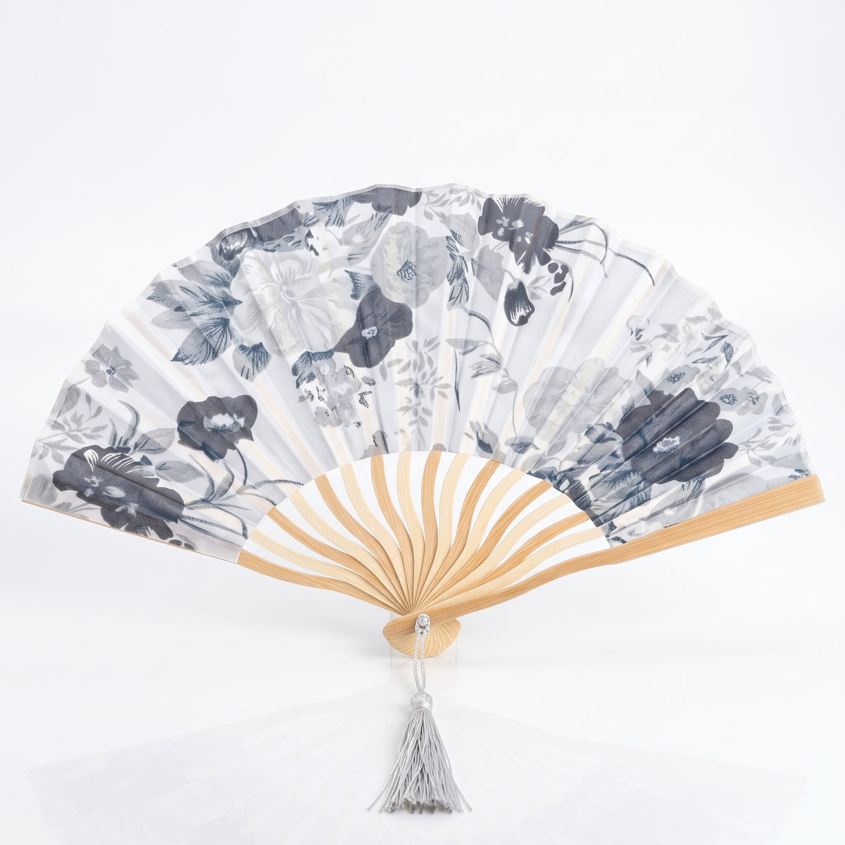 Éventail japonais fleuri blanc en forme de coquille, fleurs grises sur tissu clair, pompon blanc