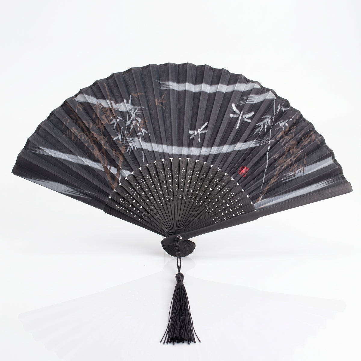 Éventail japonais nature noir ouvert, bambous et libellules sur fond noir, sceau rouge et pompon noir
