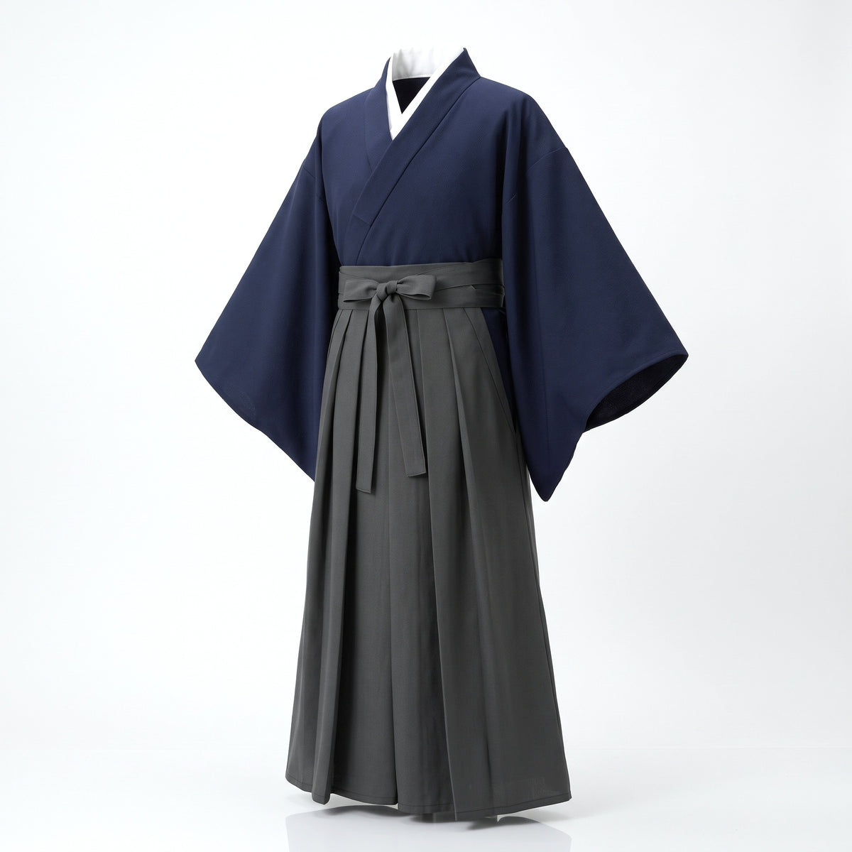 Kimono japonais homme bleu marine au col blanc et hakama gris plissé noué à la taille, vu de trois quarts sur fond clair