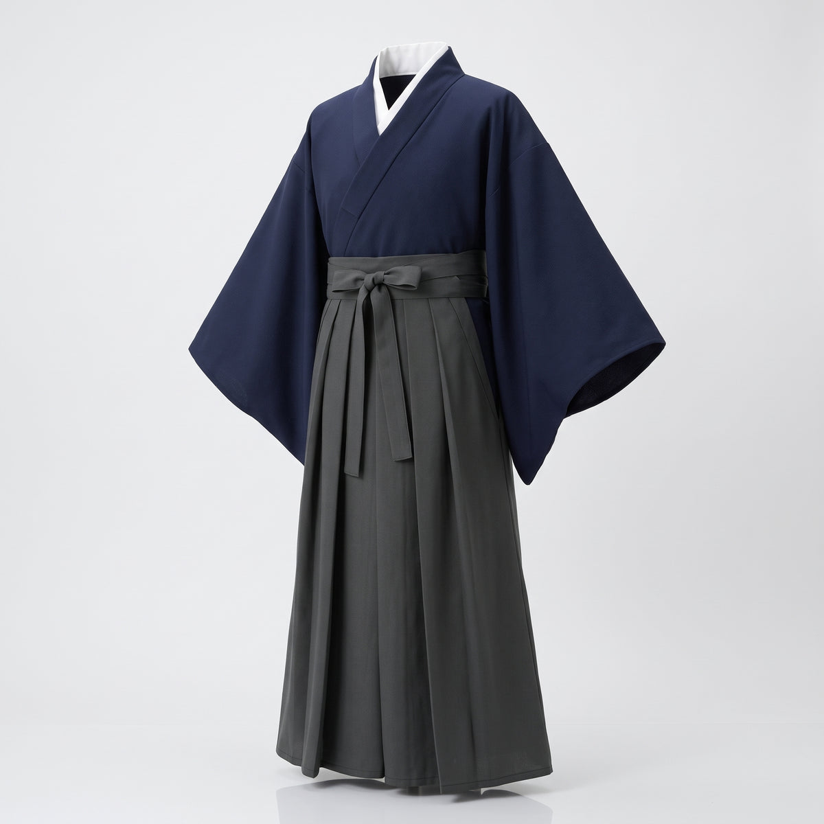 Kimono japonais homme bleu marine au col blanc et hakama gris plissé noué à la taille, vu de trois quarts sur fond clair