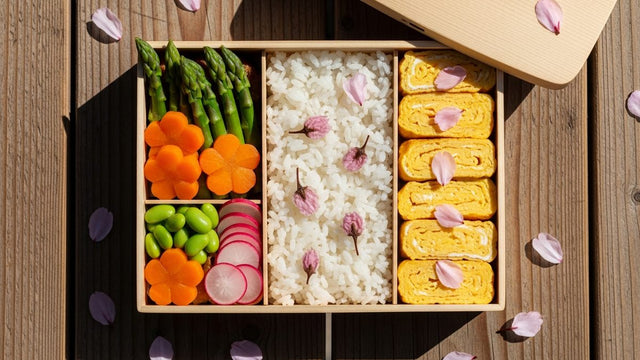 Boîte bento japonaise ouverte avec décoration sakura, riz coloré et légumes printaniers pour le Golden Week