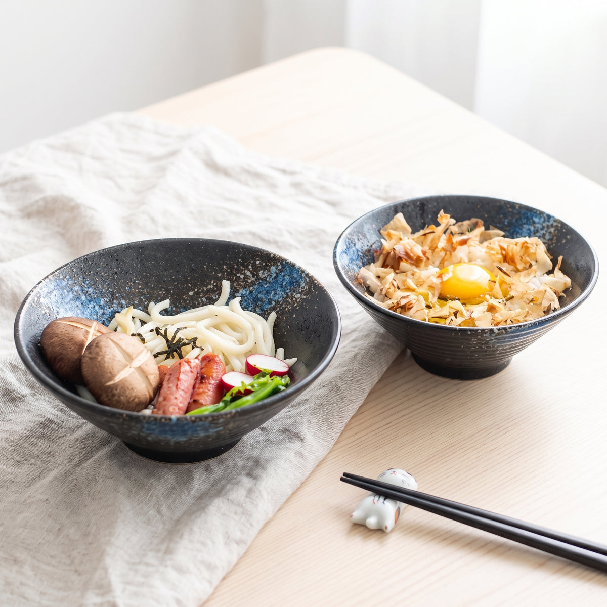 Deux bols à ramen japonais rustiques Bleu servis sur une table en bois, nouilles d'un côté, œuf et bonite de l'autre