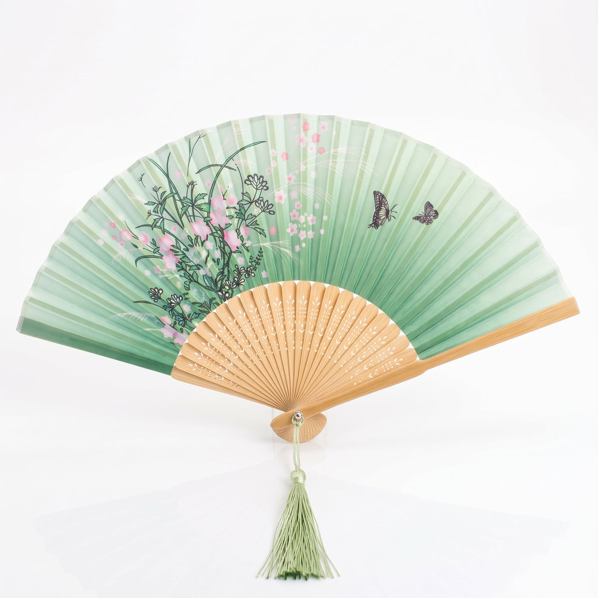 Éventail japonais nature vert ouvert, herbes en fleurs et papillons, monture claire ajourée et pompon vert pâle