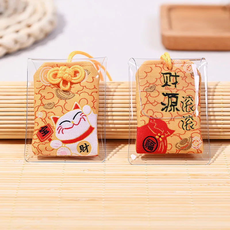 Omamori jaune japonais brodé avec Maneki-Neko et lingots d'or pour attirer la richesse et la prospérité.