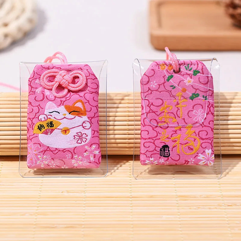 Omamori rose japonais brodé avec Maneki-Neko et fleurs de cerisier pour le bonheur et la paix.