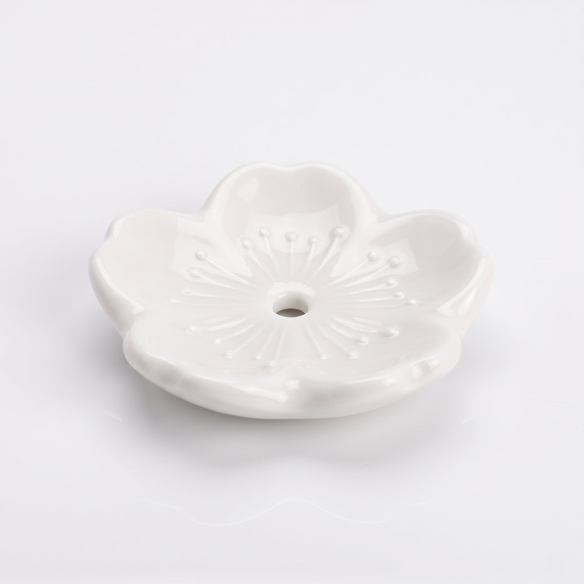 Porte-encens japonais sakura en céramique blanche, fleur de cerisier à cinq pétales et trou central, vu de trois quarts