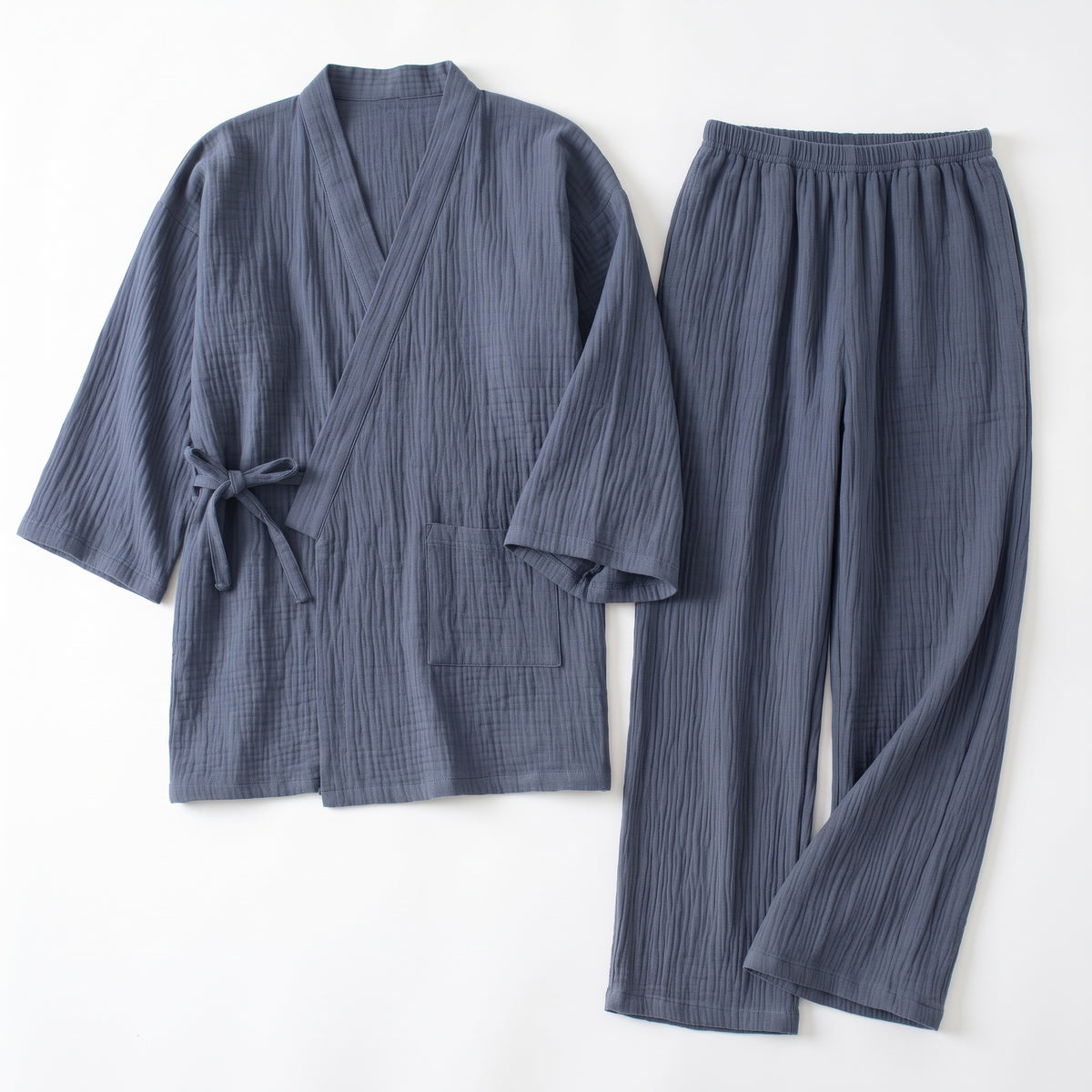 Pyjama japonais bleu ardoise en gaze de coton froissée, haut croisé noué et pantalon, posés à plat sur fond clair