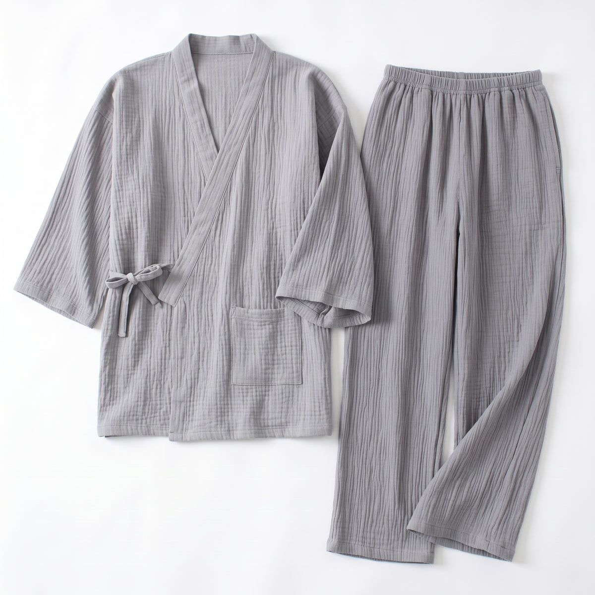 Pyjama japonais gris en gaze de coton froissée, haut croisé noué et pantalon, posés à plat sur fond clair
