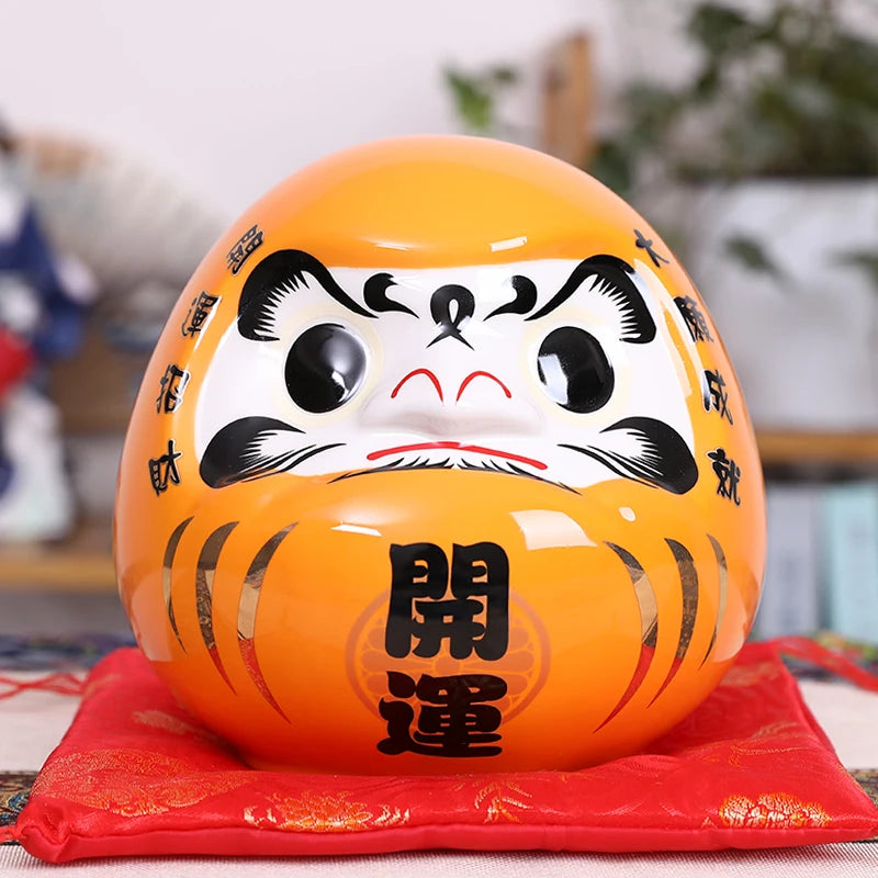 Tirelire Daruma orange japonaise en céramique brillante pour attirer la richesse et la prospérité financière.